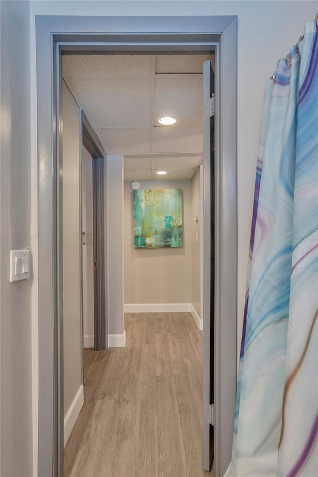 hallway featuring light hardwood / wood-style flooring and a paneled ceiling