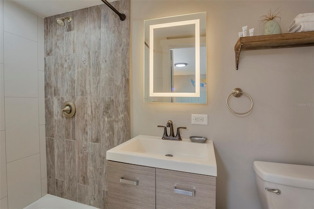 bathroom with vanity, toilet, and tiled shower