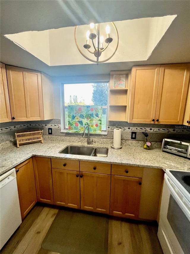 kitchen featuring an inviting chandelier, light stone countertops, white appliances, wood-type flooring, and sink