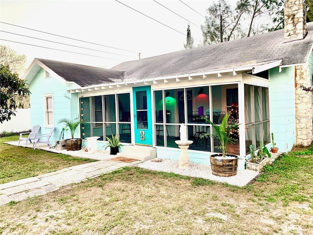 1478 Alternate Keene Rd, Largo, FL 33771 - rear view of property featuring a sunroom, a shingled roof, a yard, and a chimney