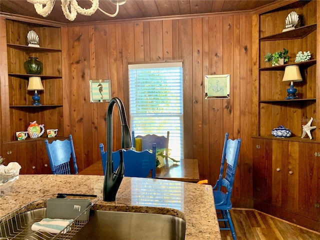 dining room with crown molding, wood walls, sink, wood ceiling, and hardwood / wood-style flooring