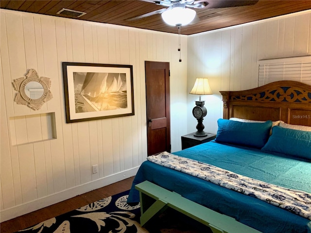 bedroom with dark wood-type flooring, ceiling fan, wood ceiling, and wooden walls