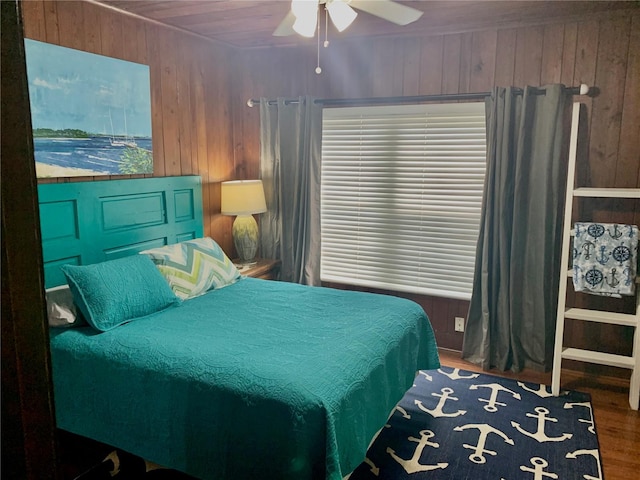 bedroom with hardwood / wood-style floors, ceiling fan, and wooden walls