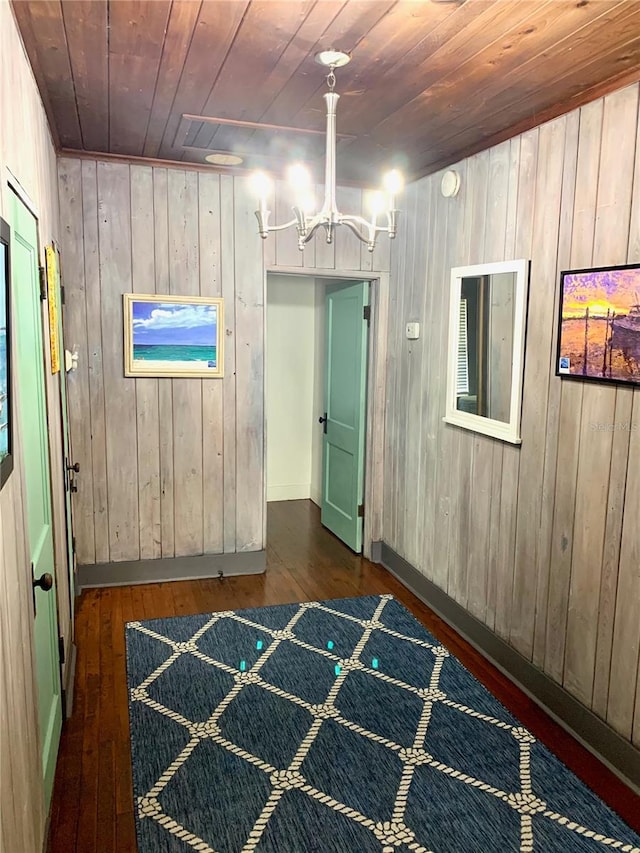 interior space featuring wood ceiling, a notable chandelier, wooden walls, and dark hardwood / wood-style flooring