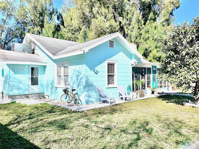 back of property with a lawn and a sunroom