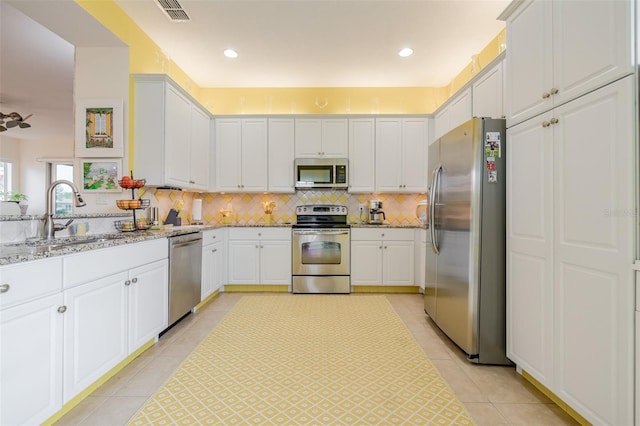 kitchen with stainless steel appliances, sink, decorative backsplash, light stone counters, and white cabinets