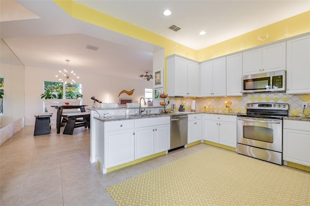 kitchen featuring plenty of natural light, kitchen peninsula, appliances with stainless steel finishes, and a chandelier