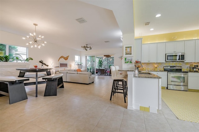 kitchen featuring a wealth of natural light, hanging light fixtures, stainless steel appliances, and white cabinets