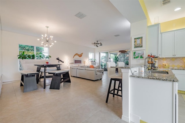 kitchen with a healthy amount of sunlight, a breakfast bar area, decorative light fixtures, and white cabinetry