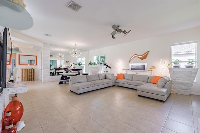 living room with a wealth of natural light, light tile patterned floors, and a notable chandelier