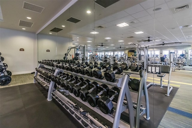 gym featuring a healthy amount of sunlight, a paneled ceiling, and ceiling fan