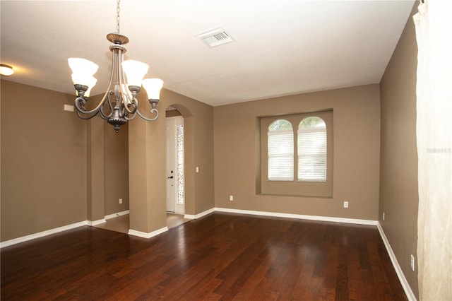 spare room with an inviting chandelier and wood-type flooring