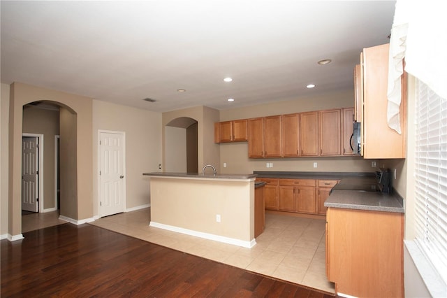 kitchen featuring range, a center island with sink, sink, and light hardwood / wood-style floors