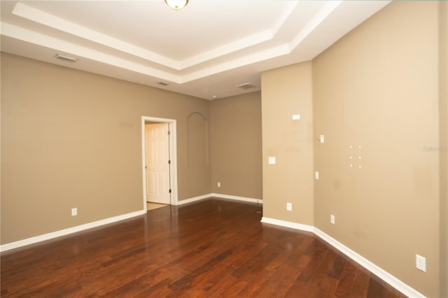 spare room with dark wood-type flooring and a raised ceiling