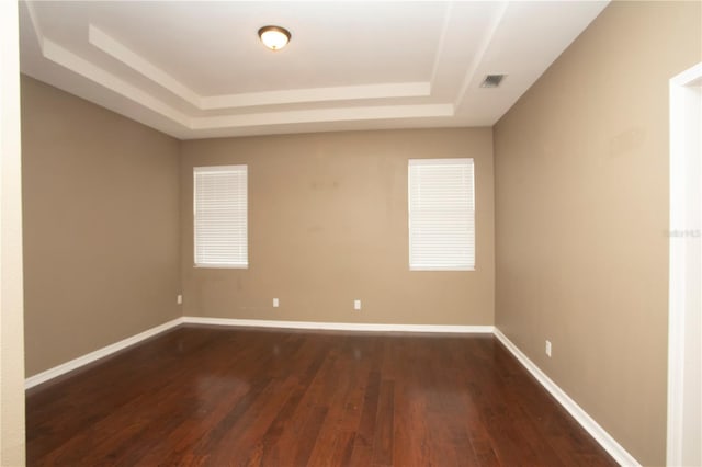 spare room with hardwood / wood-style floors and a raised ceiling