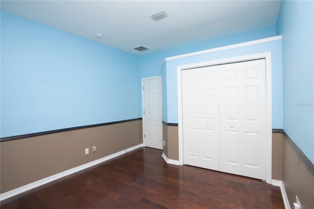 unfurnished bedroom with a closet and dark hardwood / wood-style floors