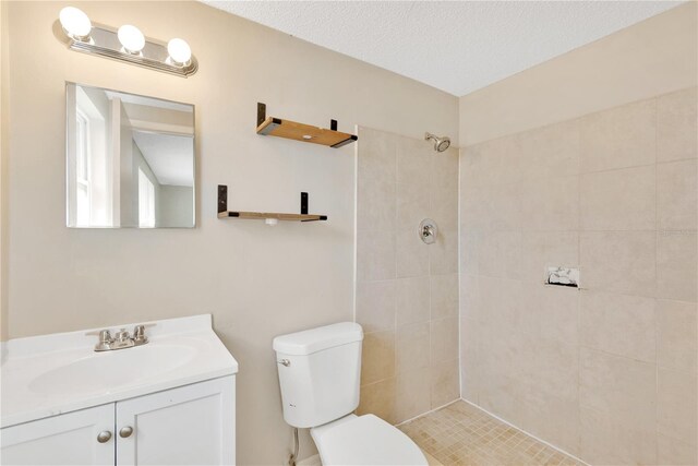 bathroom featuring tiled shower, toilet, a textured ceiling, and vanity