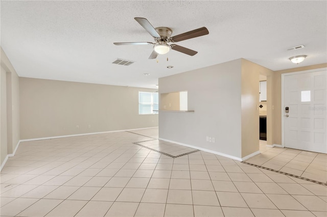 tiled spare room featuring a textured ceiling and ceiling fan