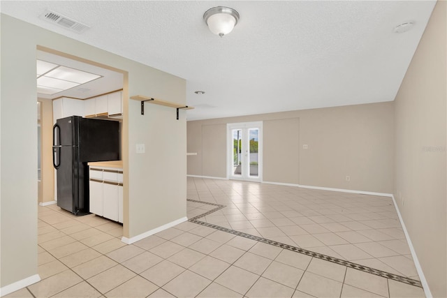 unfurnished room featuring a textured ceiling, light tile patterned floors, and french doors