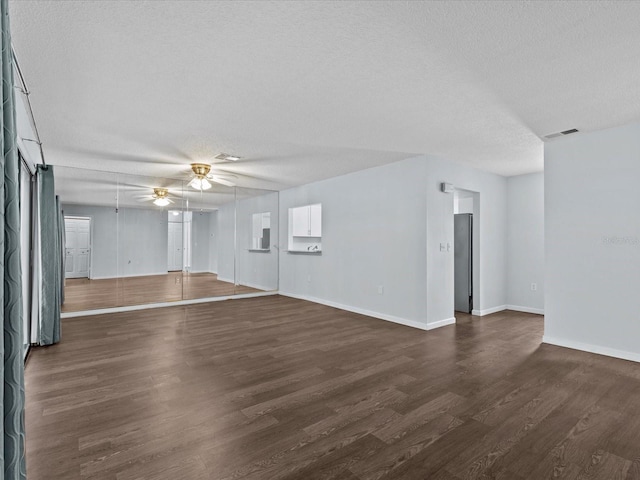 unfurnished living room featuring a textured ceiling, dark wood-type flooring, and ceiling fan