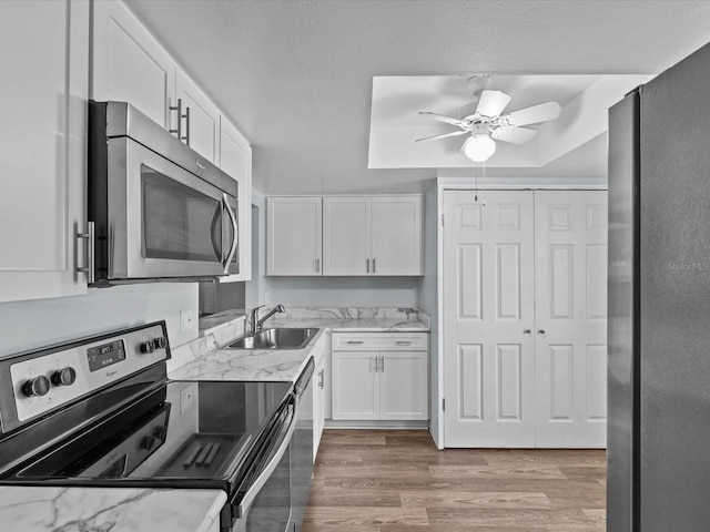 kitchen featuring light hardwood / wood-style flooring, stainless steel appliances, white cabinetry, sink, and ceiling fan