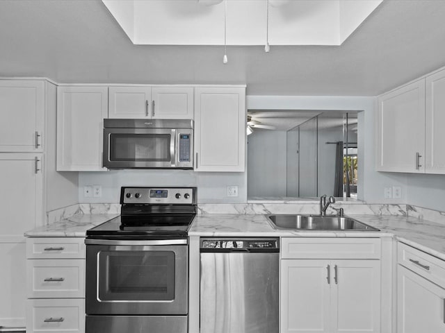 kitchen featuring white cabinets, appliances with stainless steel finishes, light stone countertops, sink, and ceiling fan