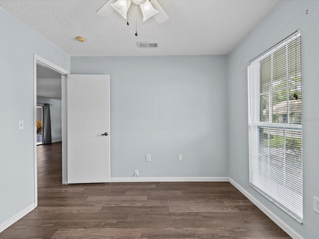 empty room with dark wood-type flooring, a textured ceiling, and ceiling fan