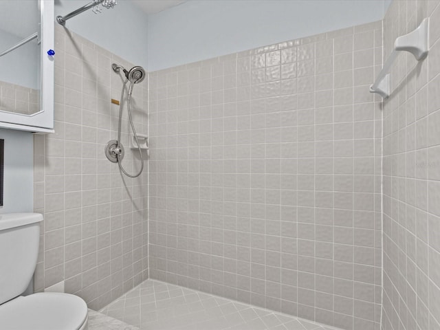 bathroom featuring toilet and a tile shower