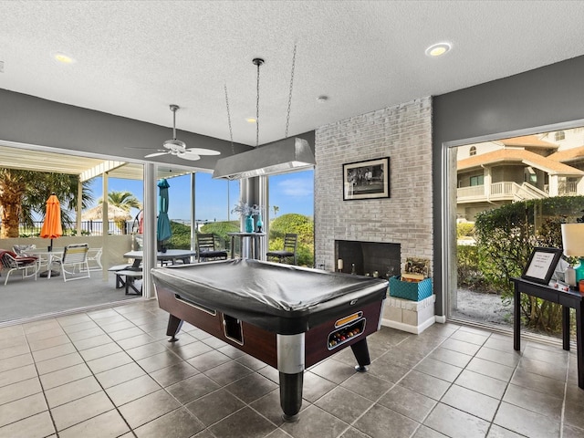 playroom with billiards, ceiling fan, a textured ceiling, and a fireplace