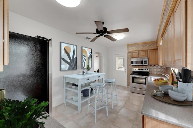 kitchen with appliances with stainless steel finishes, tasteful backsplash, light brown cabinets, ceiling fan, and sink