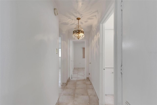 corridor featuring an inviting chandelier and light tile patterned floors