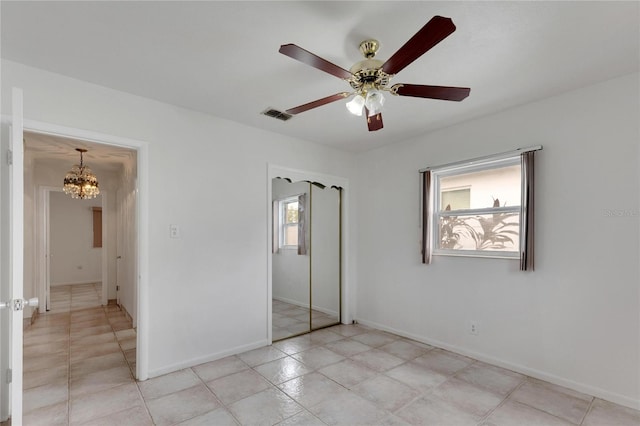 unfurnished bedroom featuring light tile patterned floors, ceiling fan with notable chandelier, a closet, and multiple windows