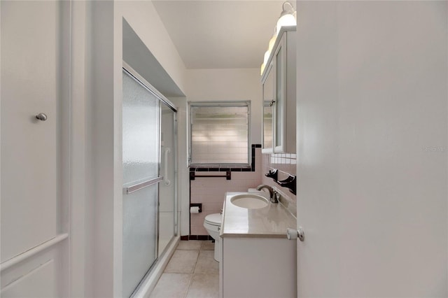 bathroom with tile walls, an enclosed shower, vanity, and toilet