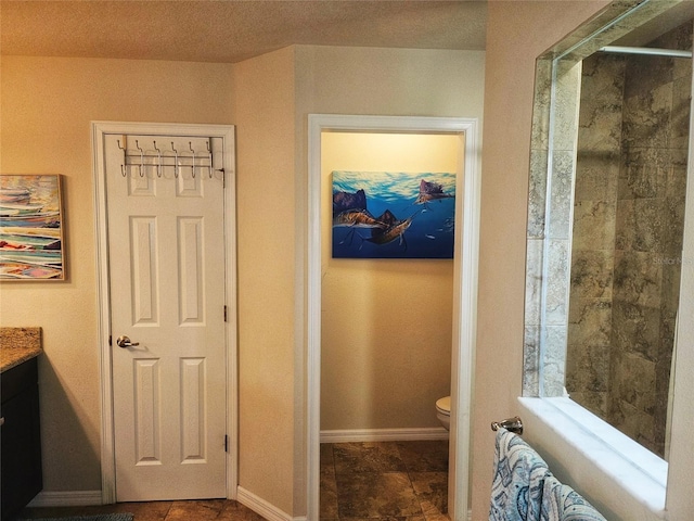 bathroom with a shower with door, vanity, a textured ceiling, and toilet