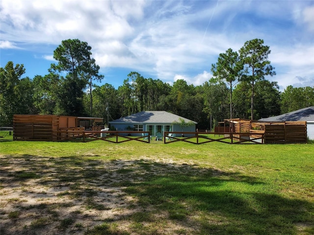 view of yard featuring an outdoor structure, a wooded view, and an exterior structure