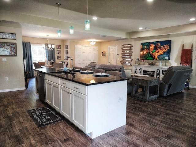 kitchen featuring dark countertops, open floor plan, dark wood-style flooring, and a sink