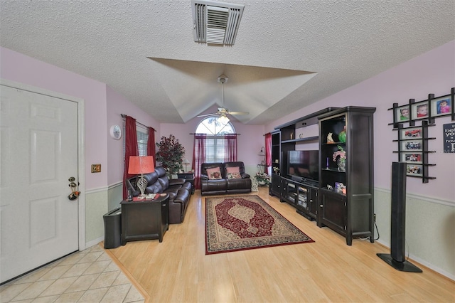 living room featuring lofted ceiling, a textured ceiling, ceiling fan, and light hardwood / wood-style floors