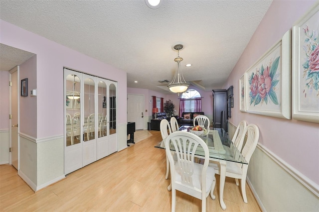 dining area with baseboards, light wood finished floors, and a textured ceiling