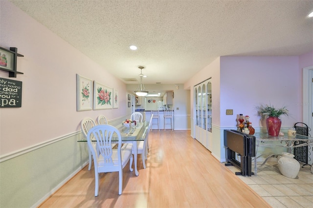 dining space featuring a textured ceiling and light wood-type flooring