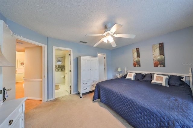 bedroom featuring a textured ceiling, connected bathroom, light carpet, and ceiling fan