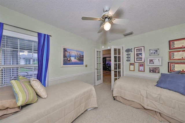 carpeted bedroom featuring visible vents, french doors, a textured ceiling, and a ceiling fan