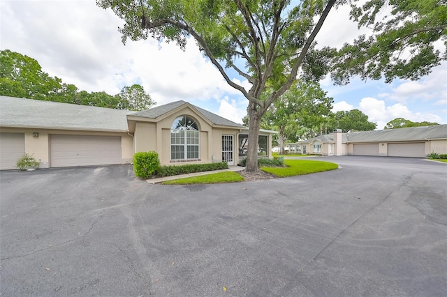 ranch-style house featuring stucco siding and aphalt driveway