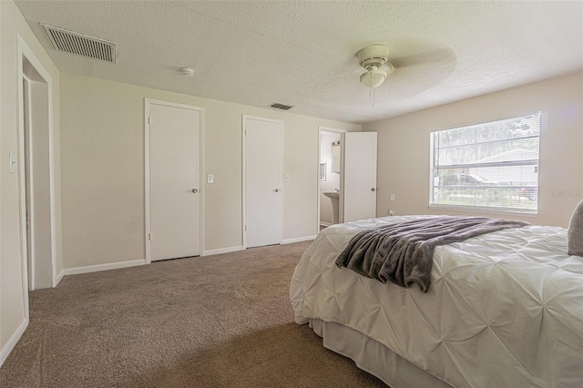 bedroom featuring a textured ceiling, carpet flooring, ceiling fan, and ensuite bath