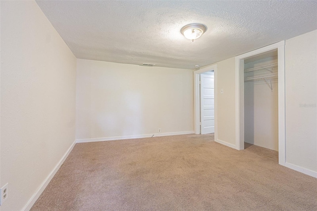 unfurnished bedroom featuring a textured ceiling, light carpet, and a closet