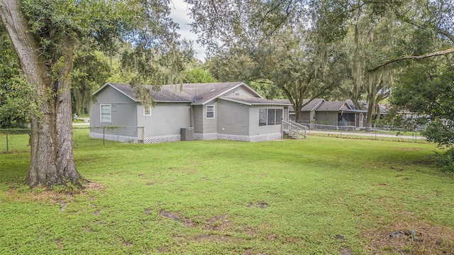 rear view of property featuring cooling unit and a yard