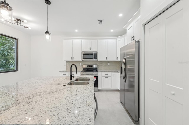 kitchen featuring hanging light fixtures, stainless steel appliances, and white cabinetry