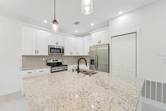 kitchen with pendant lighting, an island with sink, sink, appliances with stainless steel finishes, and white cabinets