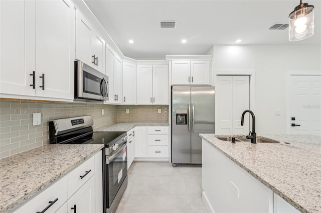 kitchen with light tile patterned floors, backsplash, stainless steel appliances, sink, and white cabinetry