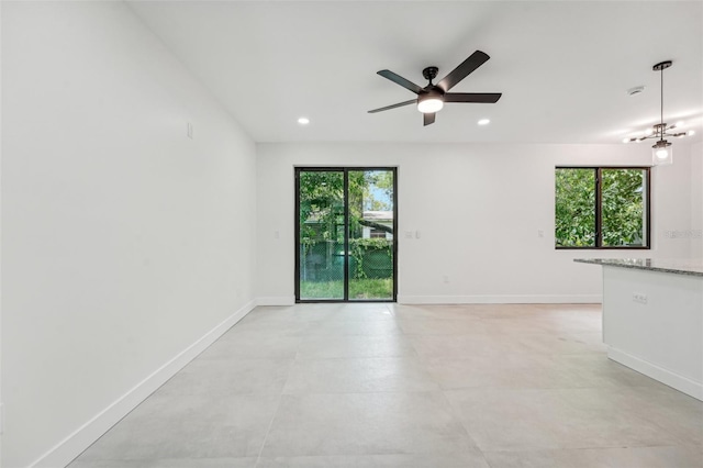 empty room with ceiling fan with notable chandelier