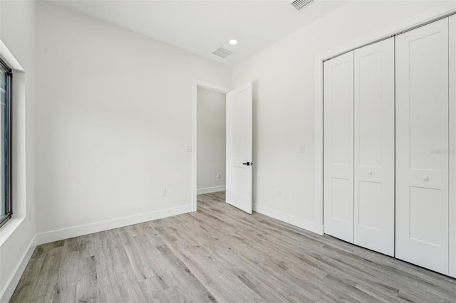 unfurnished bedroom with a closet and light hardwood / wood-style flooring